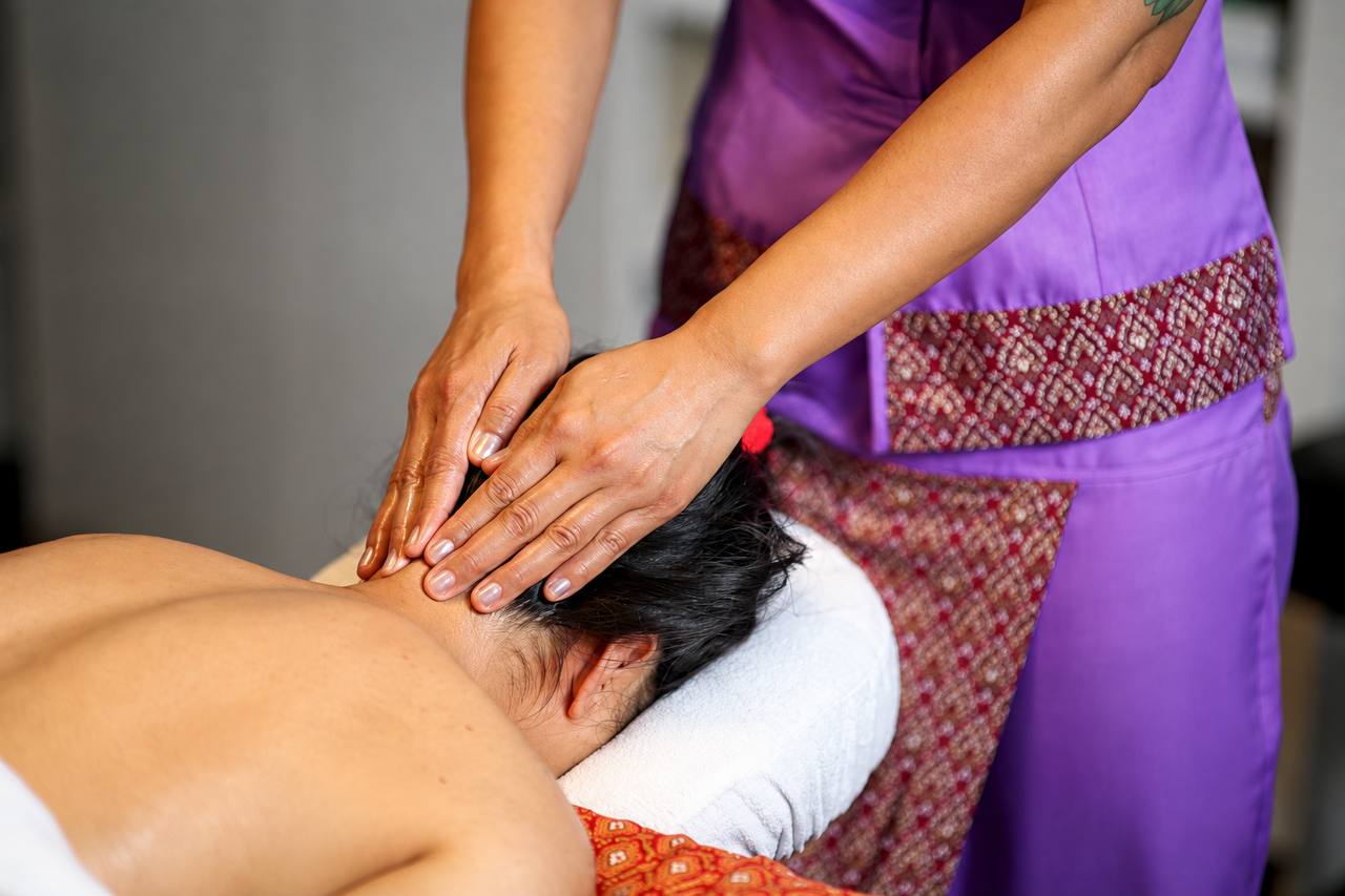 Therapist applying massage pressure to the back of a client’s neck