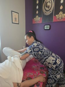 Therapist supporting a client's bent leg during assisted stretching on a massage table