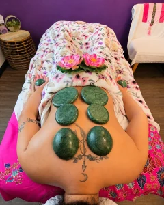 Green massage stones arranged on a client’s back during a stone massage at Siam Thai Yoga Massage.