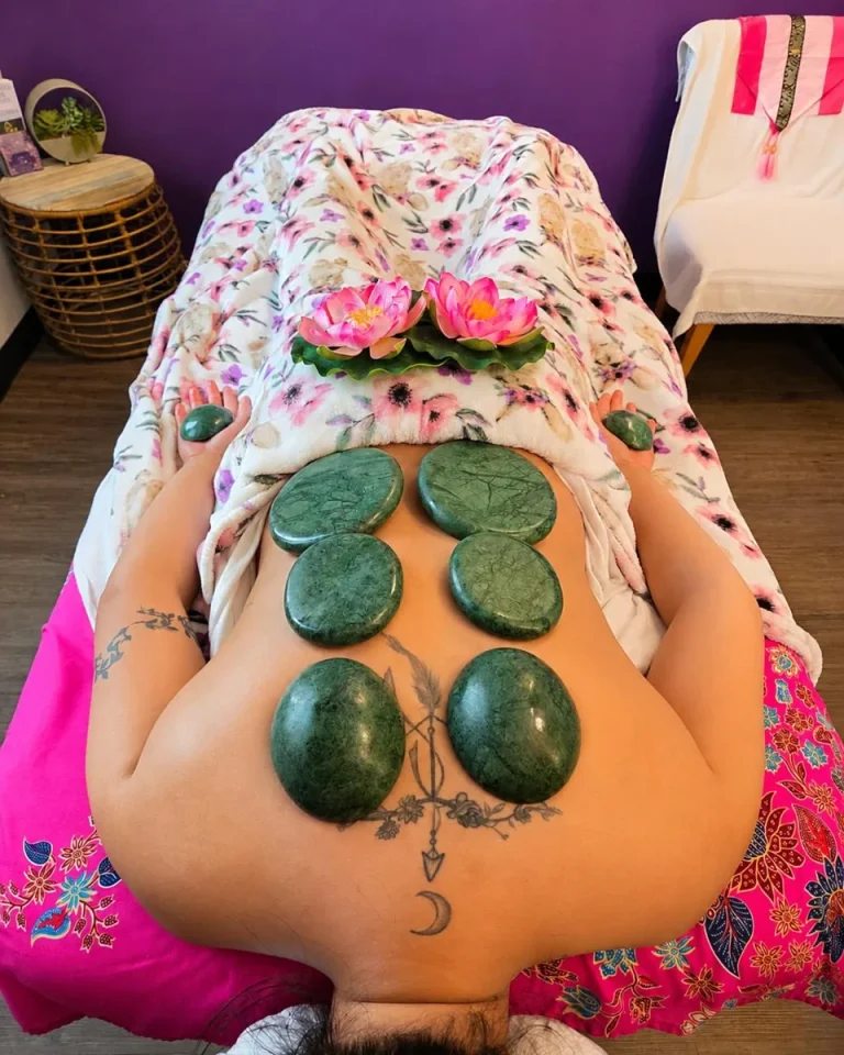 Green massage stones arranged on a client’s back during a stone massage at Siam Thai Yoga Massage.